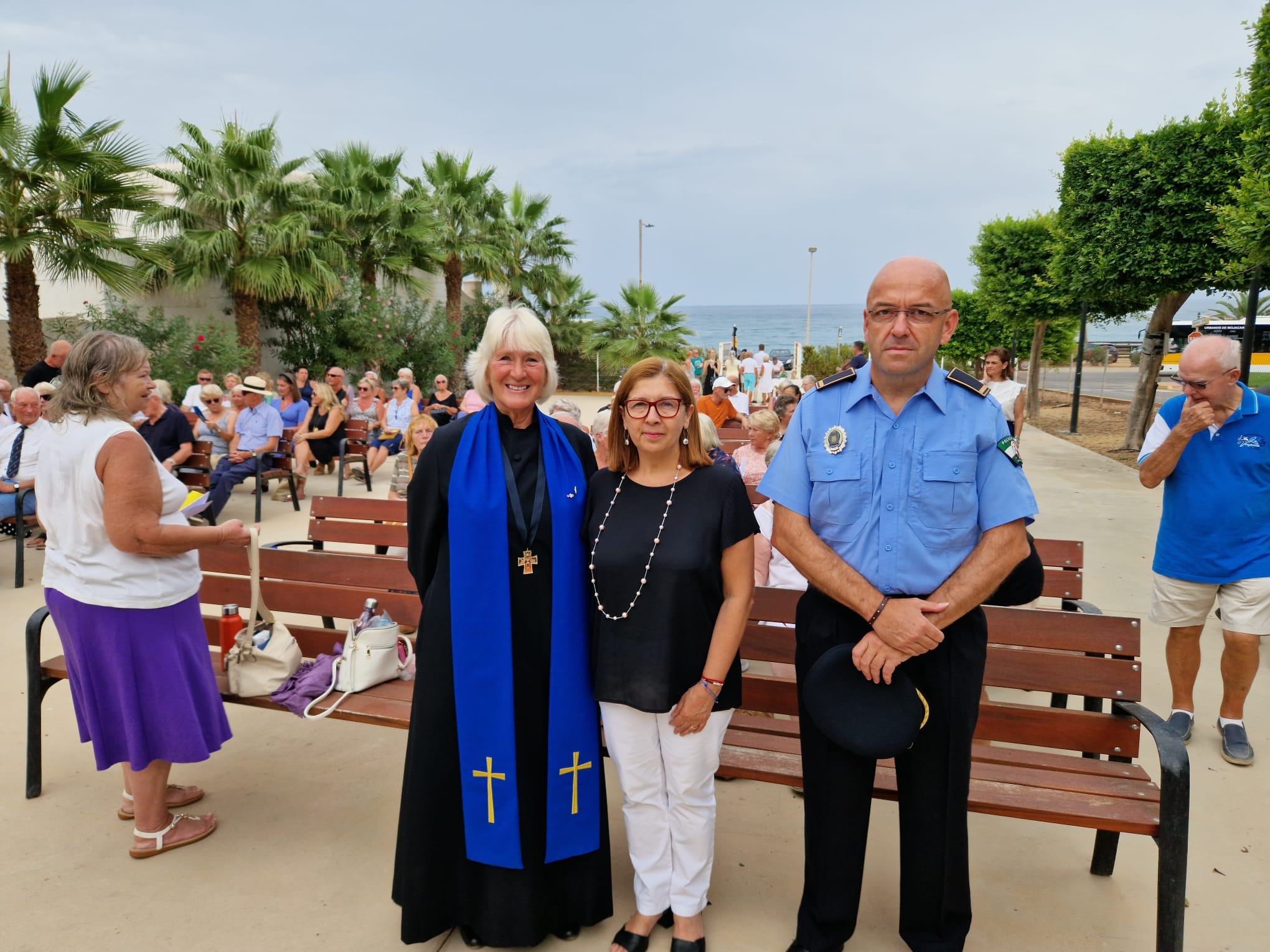 Three people at an outside memorial service for the queen.