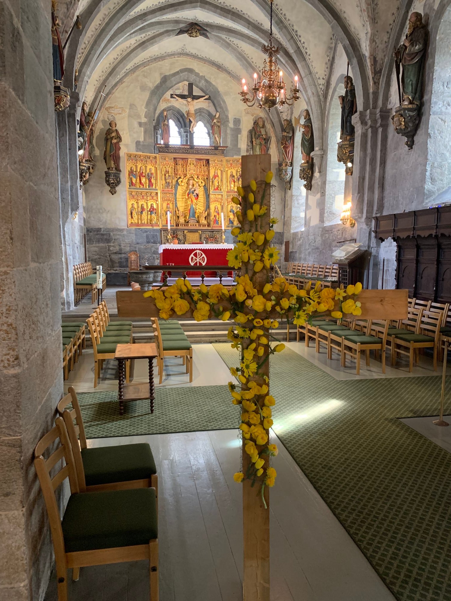 A cross covered in yellow flowers.