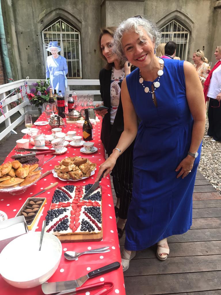 A lady cutting into a union jack cake.