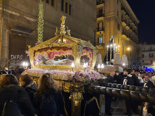 A large golden chest being paraded through a square.