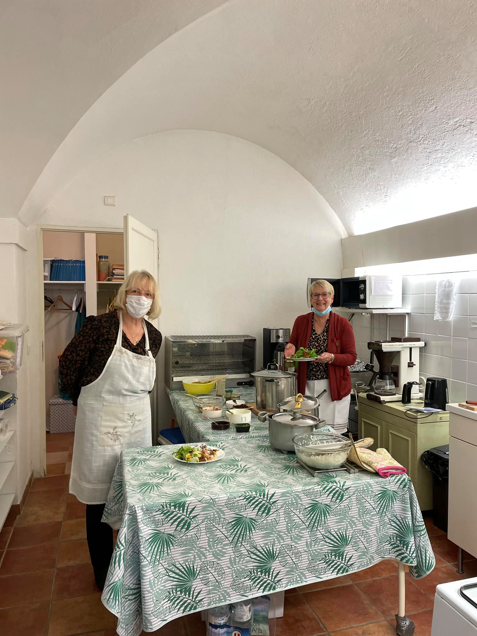 Two volunteers helping cook with masks on.