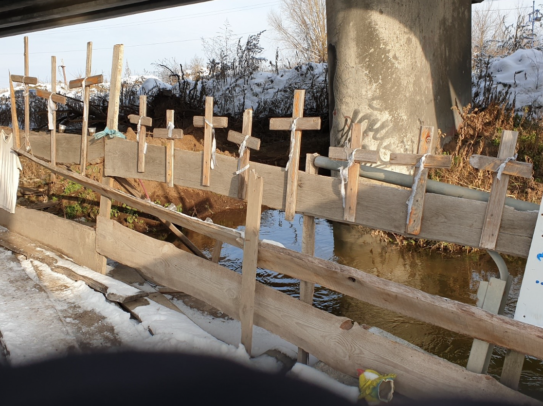 Wooden crosses nailed to the side of a bridge.