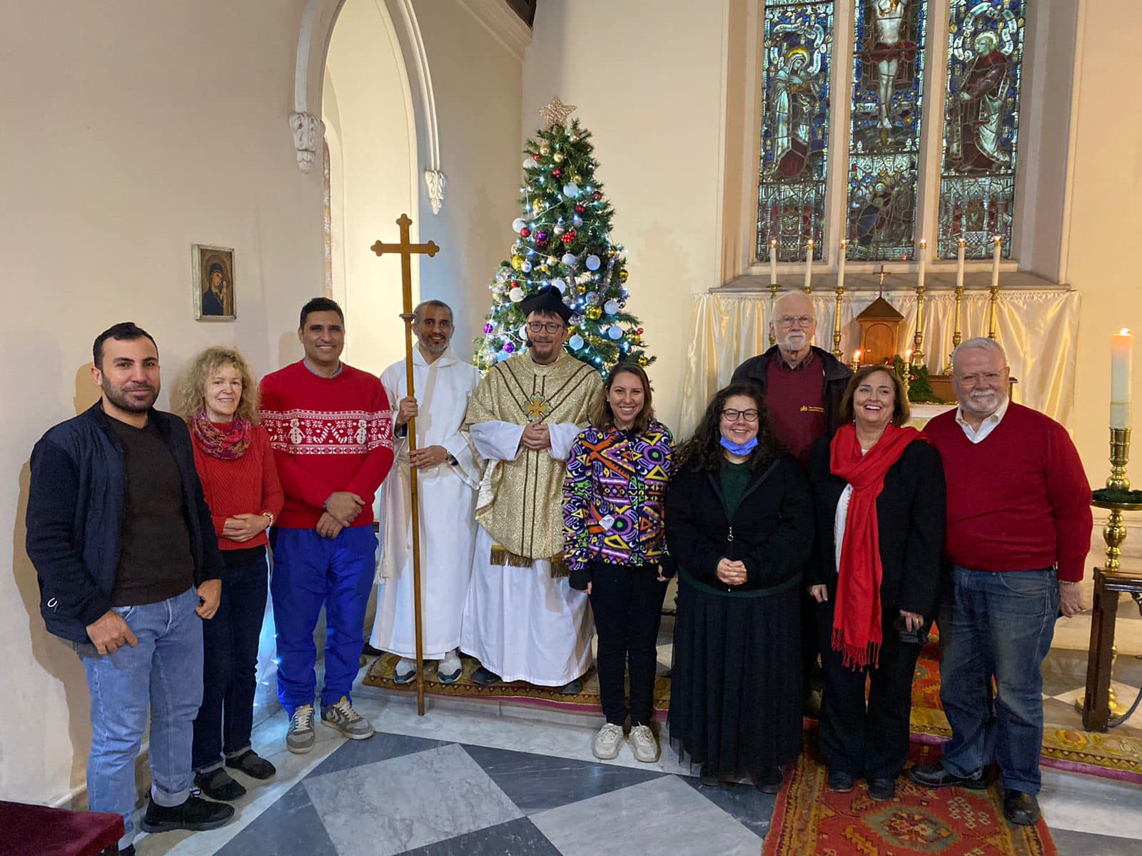 A group and clergy posed infront of a christmas tree.