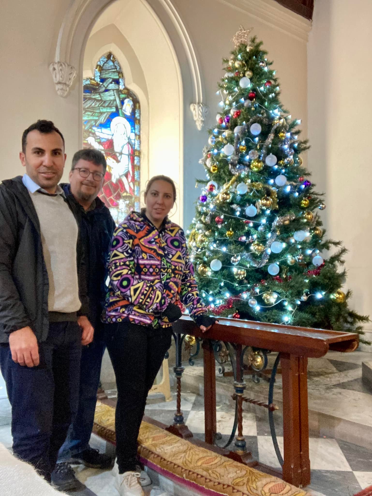 Three people standing near an ornate christmas tree.