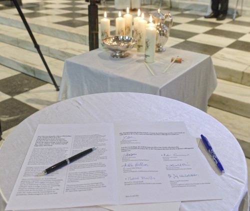 A pen laid next to multiple signatures.