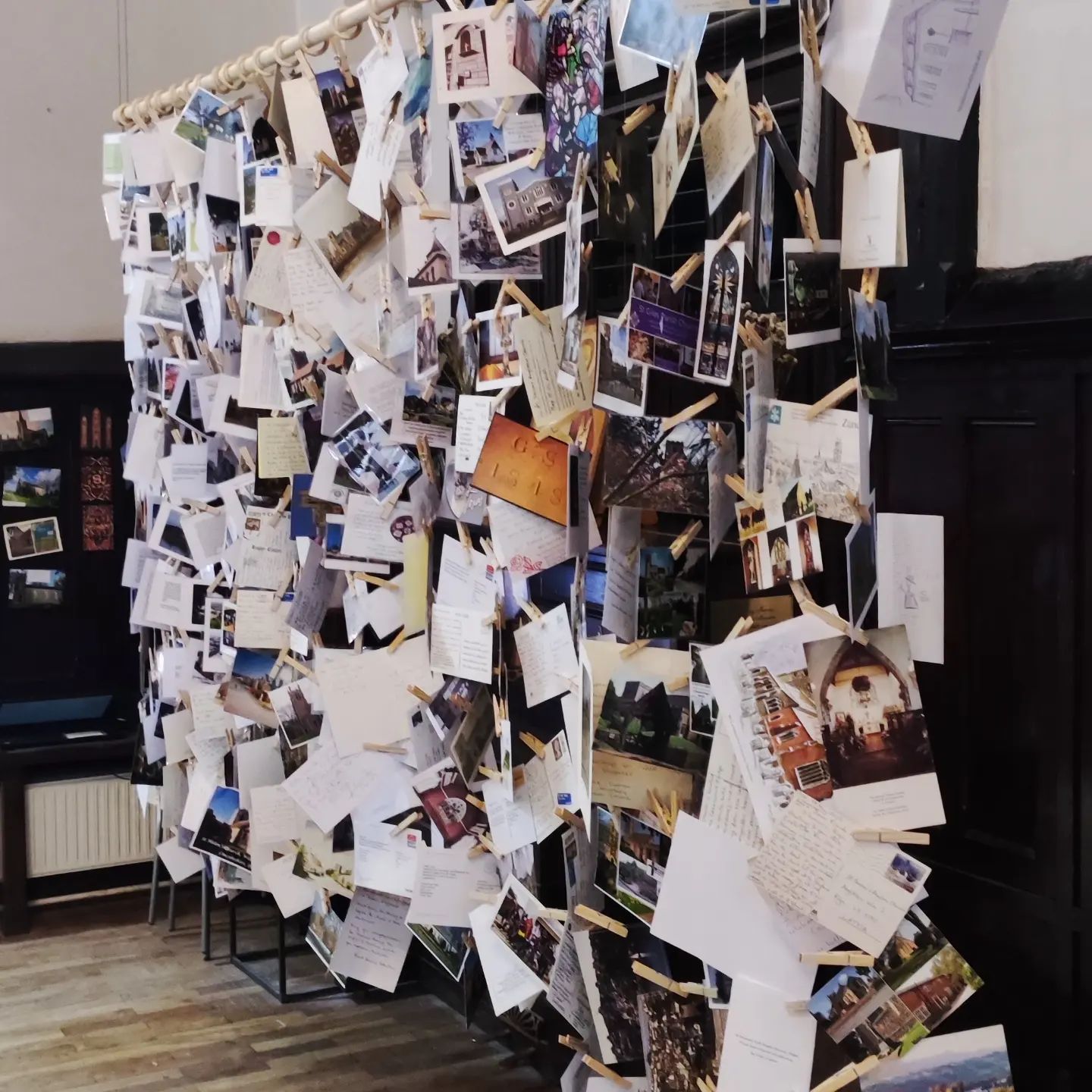 A wall with lots of postcards stuck on it.