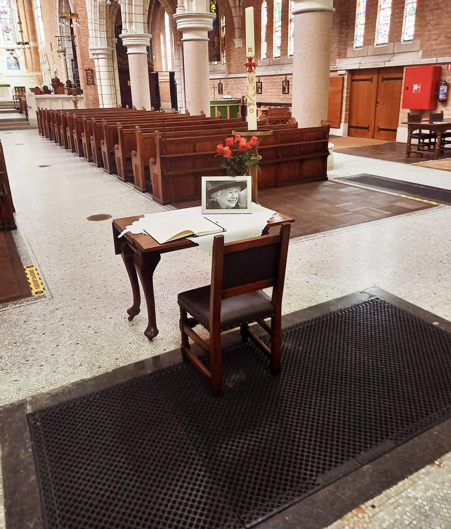 A single desk with a picture of the queen on top.