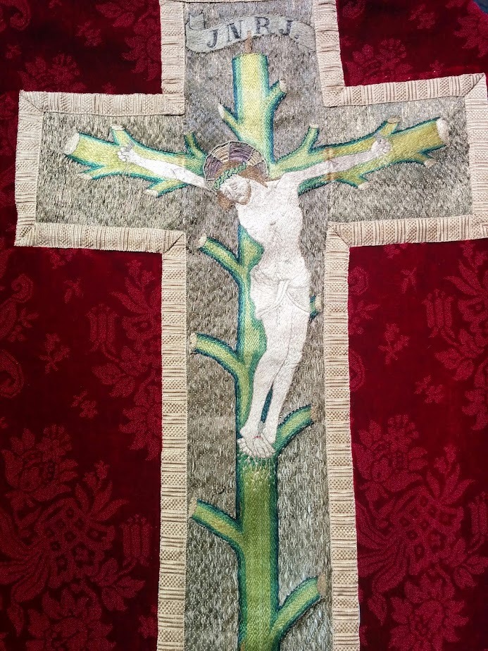 A woven banner of Jesus on a regrowing cross.