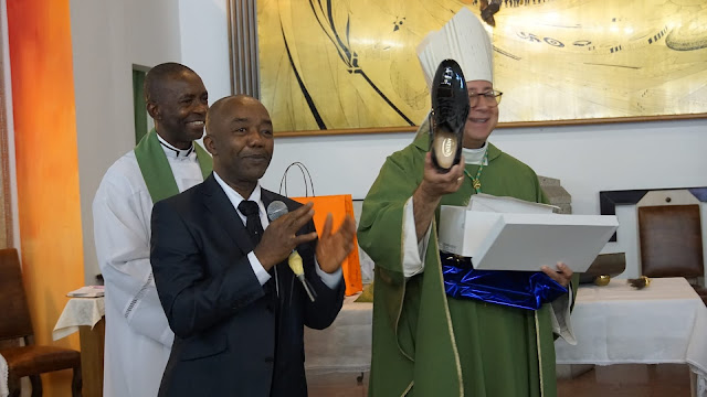 Bishop David holds up his gift of new shoes.