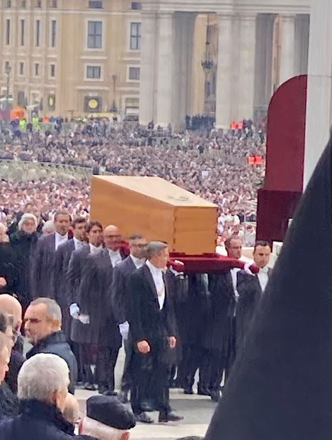 The popes coffin being carried through the crowds.