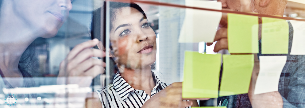 a lady looking at post it notes stuck to a glass wall