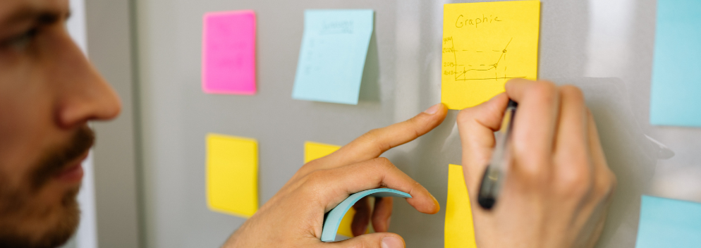 man writes on post in notes