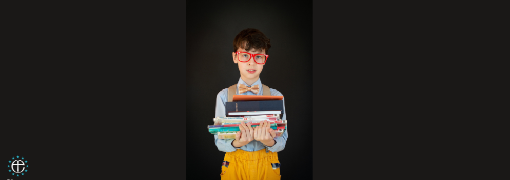 boy holding a pile of books against a black background