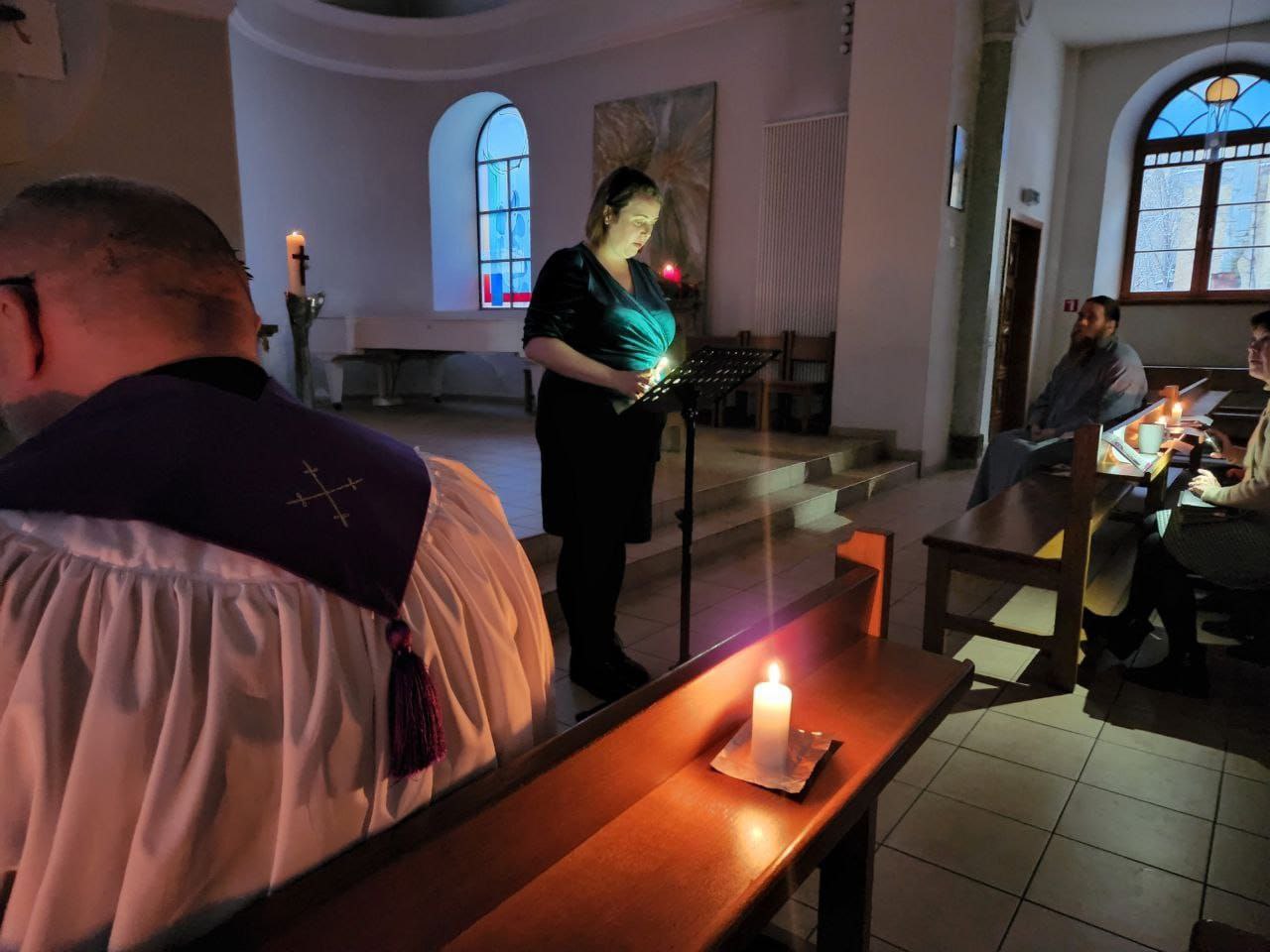 someone standing up giving a reading in a dark church