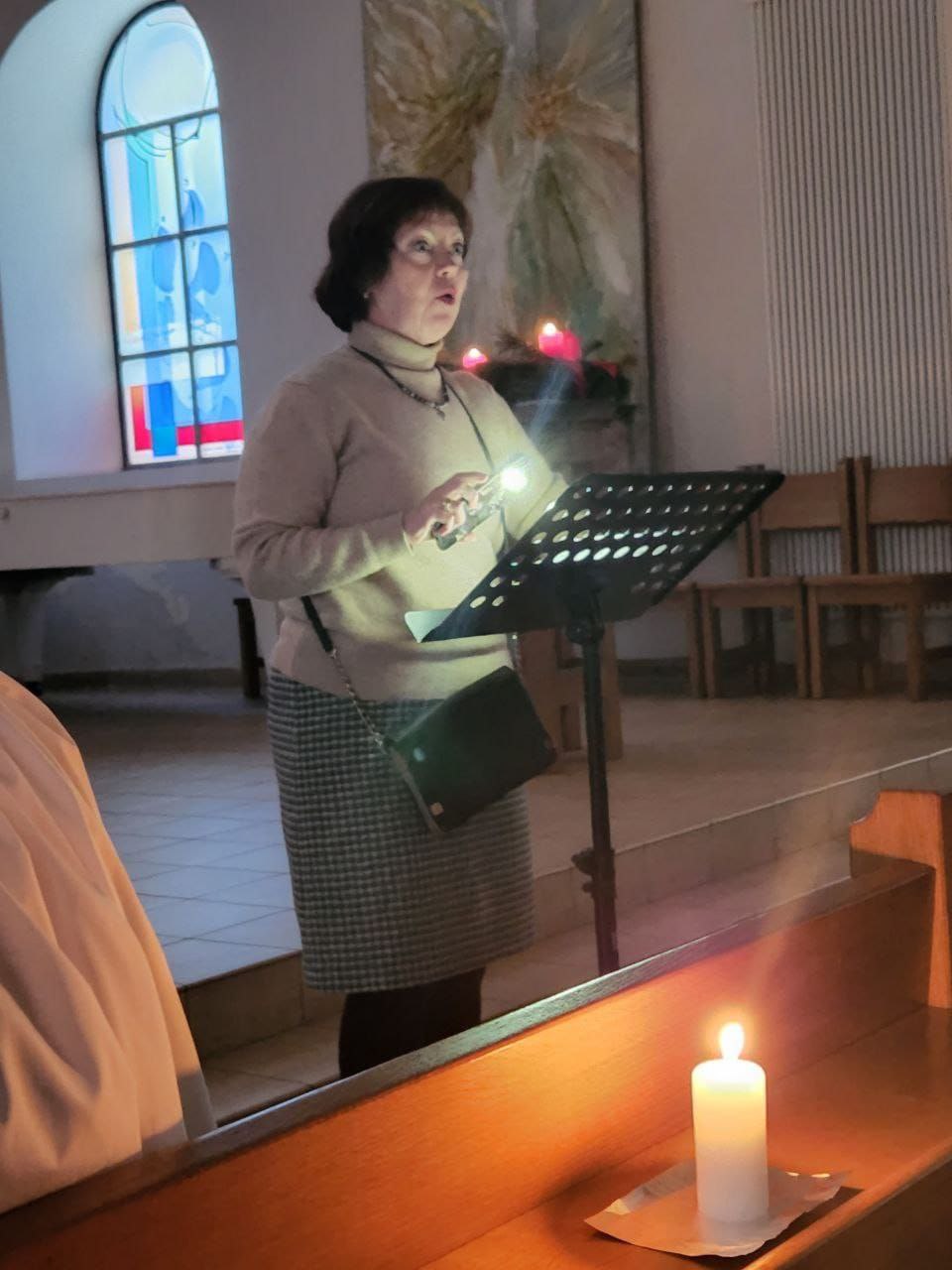 someone standing up giving a reading in a dark church