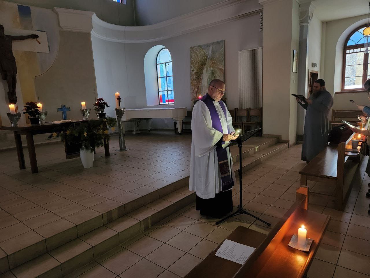 someone standing up giving a reading in a dark church
