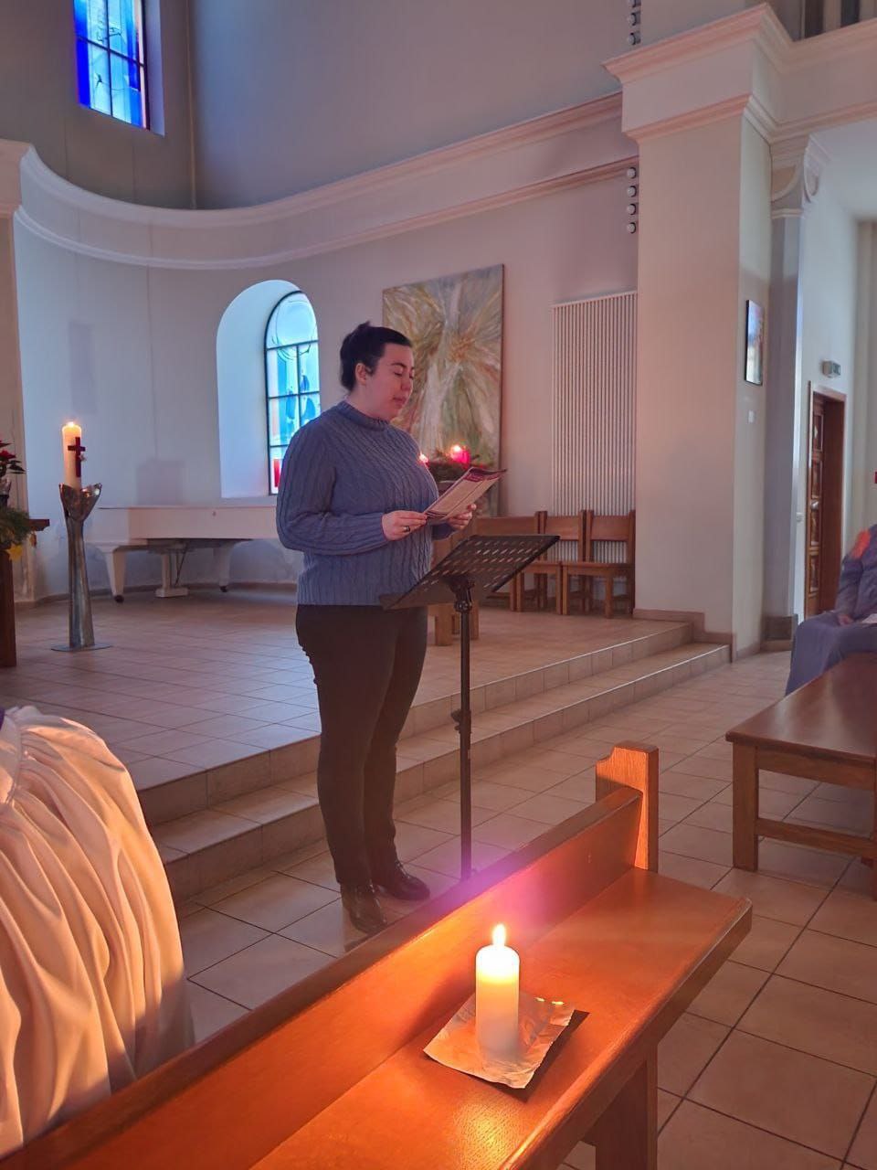 someone standing up giving a reading in a dark church