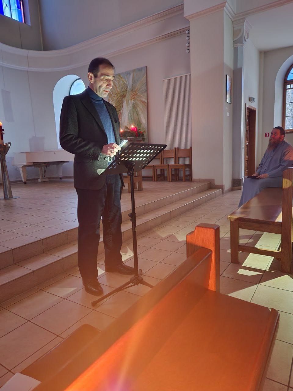 someone standing up giving a reading in a dark church