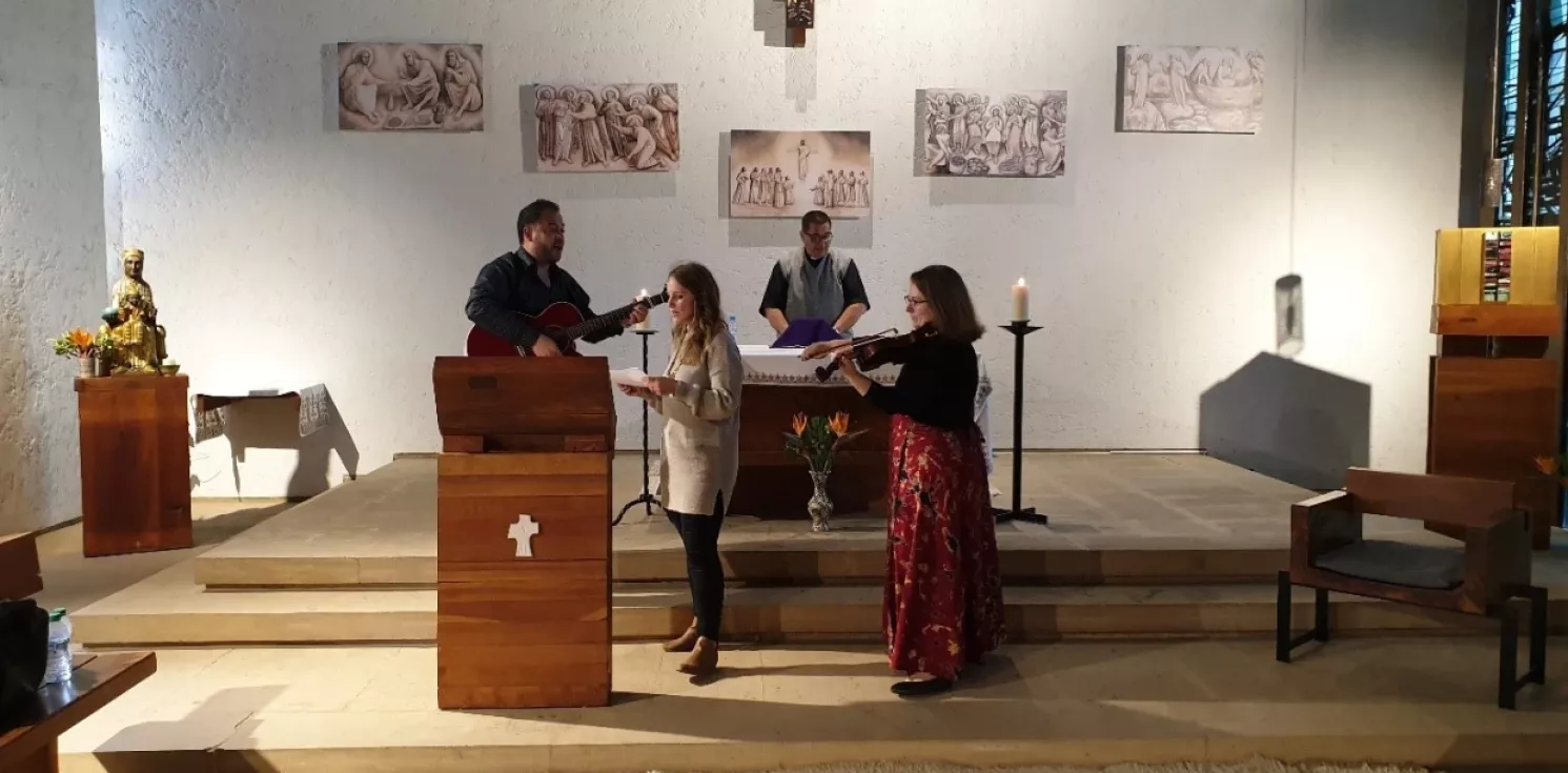 People singing and playing guitar at the front of a church.