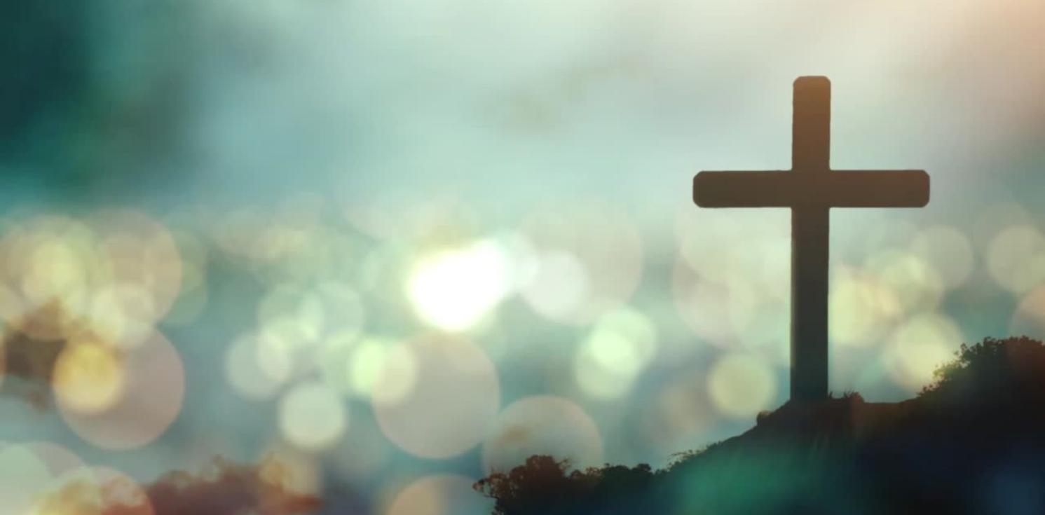 A cross silhouetted against a bokeh sky