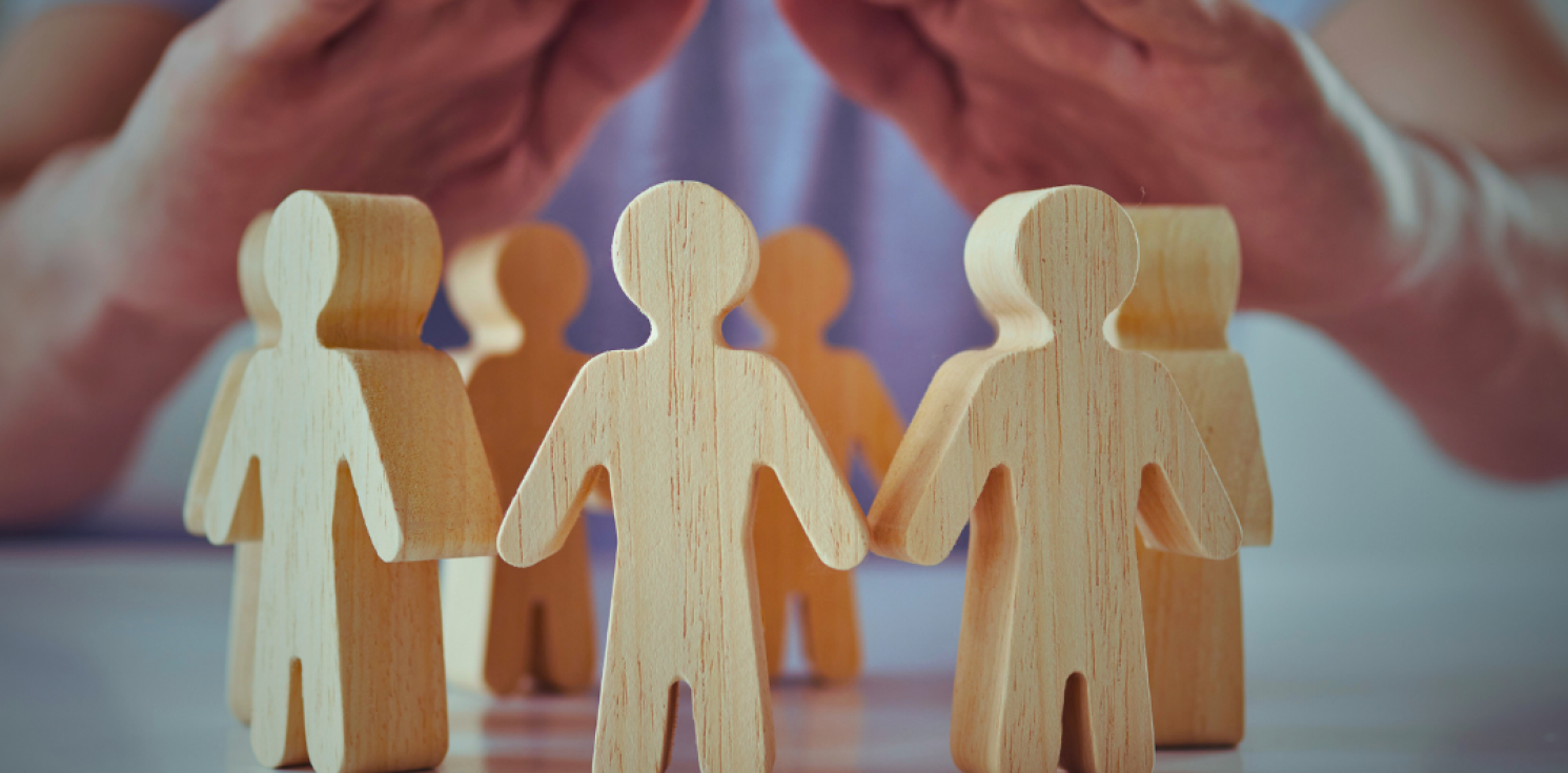 Wooden cut out people protected by hands