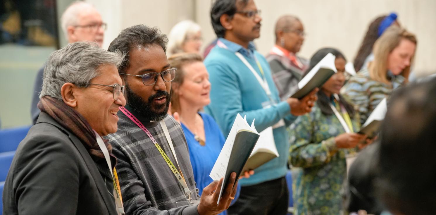People singing at a conference holding books