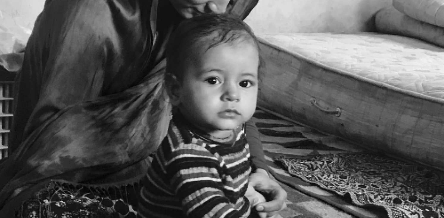 A mono image of an infant held by their mother
