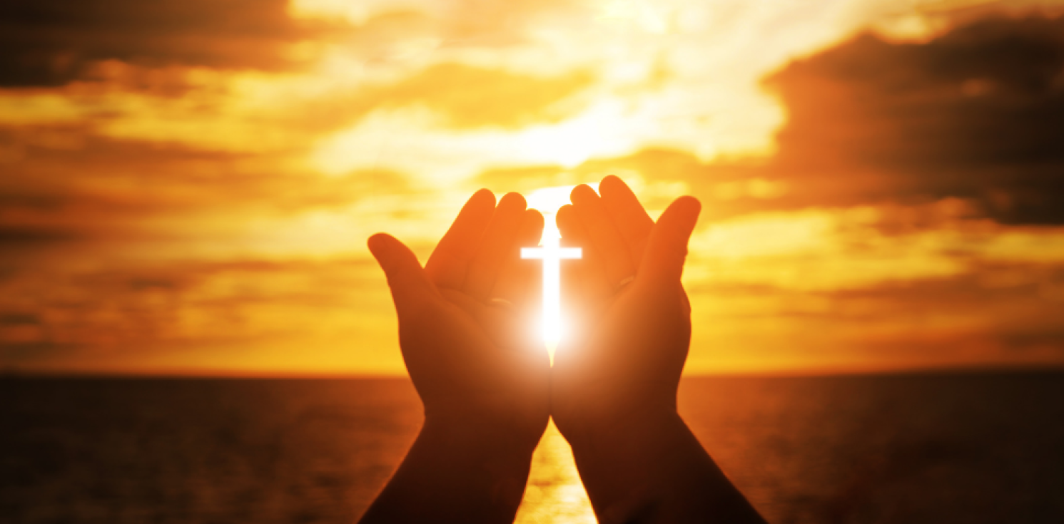 Praying hands in sunset