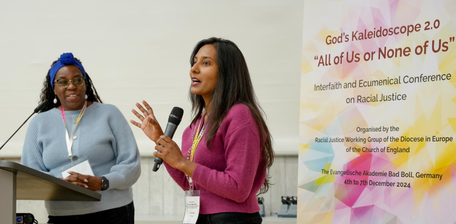 Young person speaking next to a banner of the racial justice conference and holding a mic