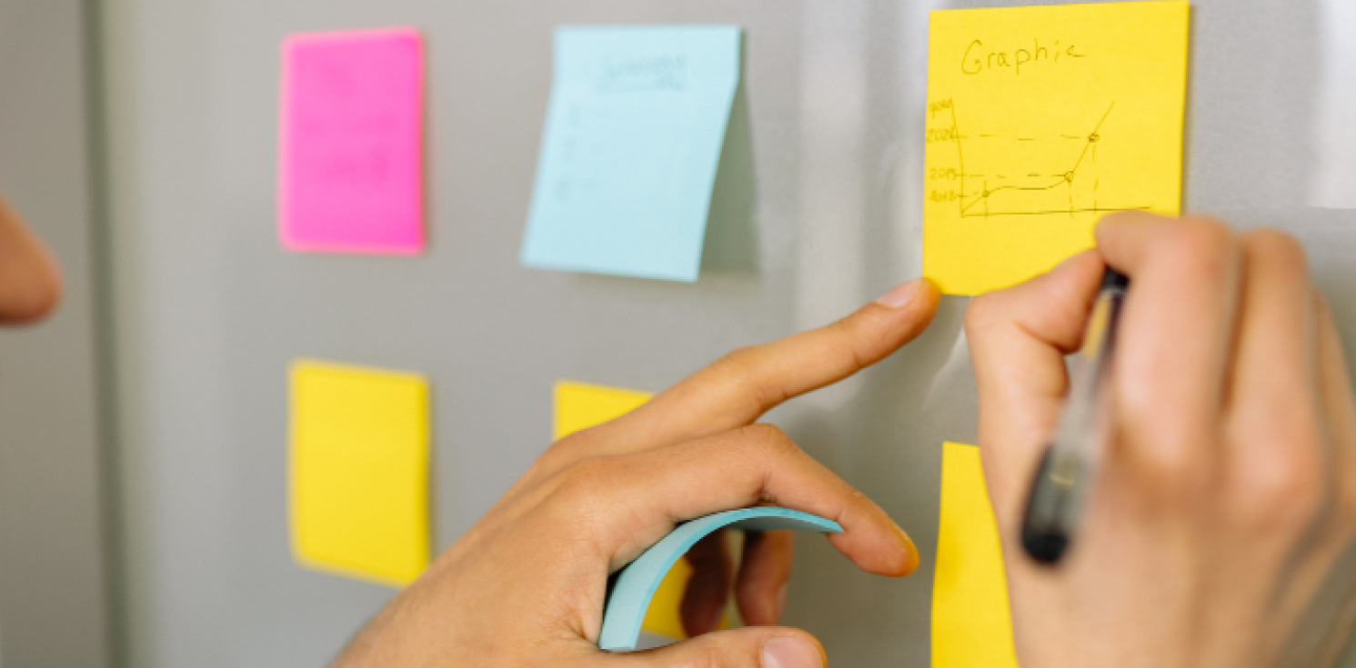 man writes on post in notes