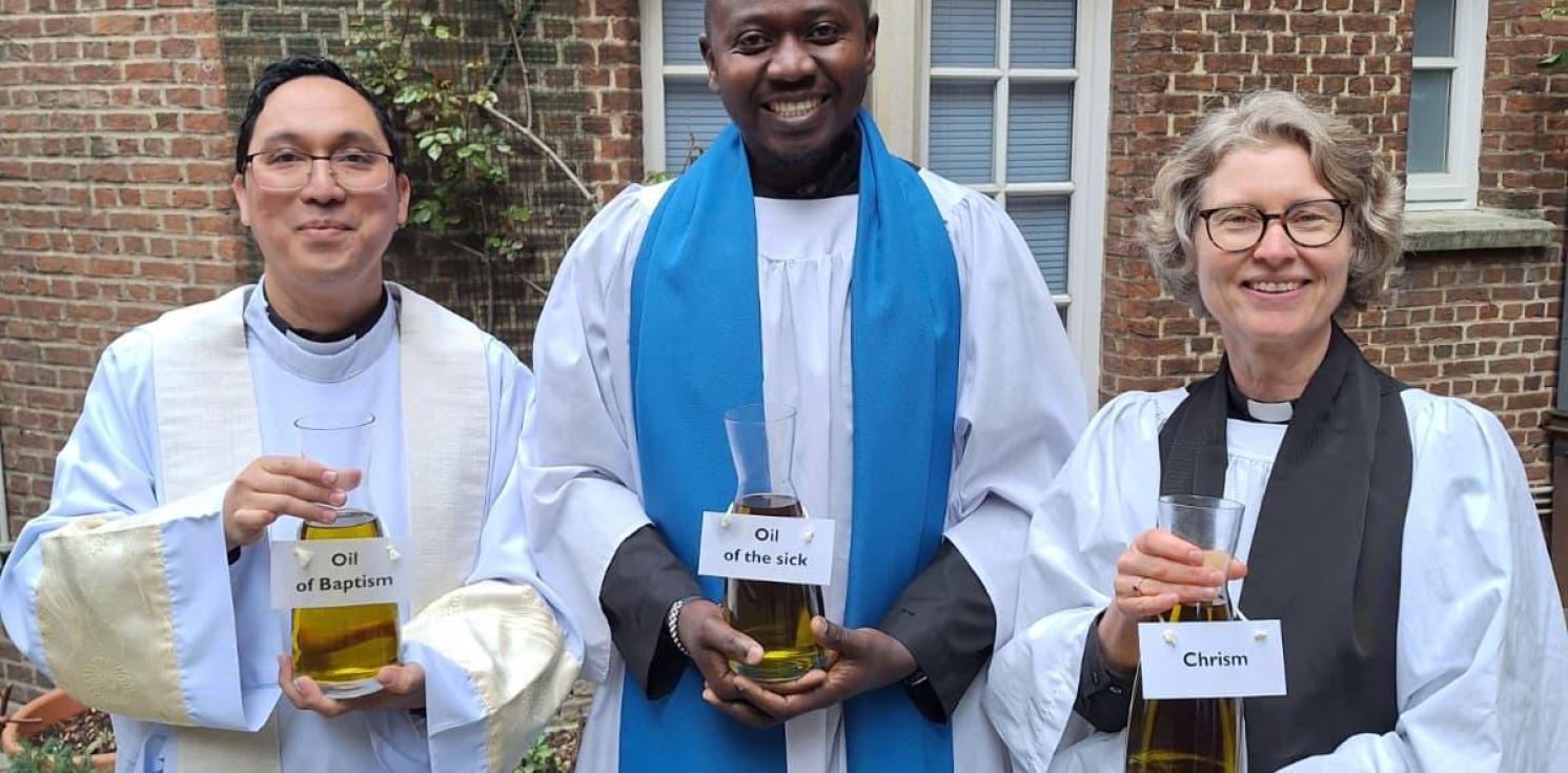 3 clergy in a row holding chrism oil