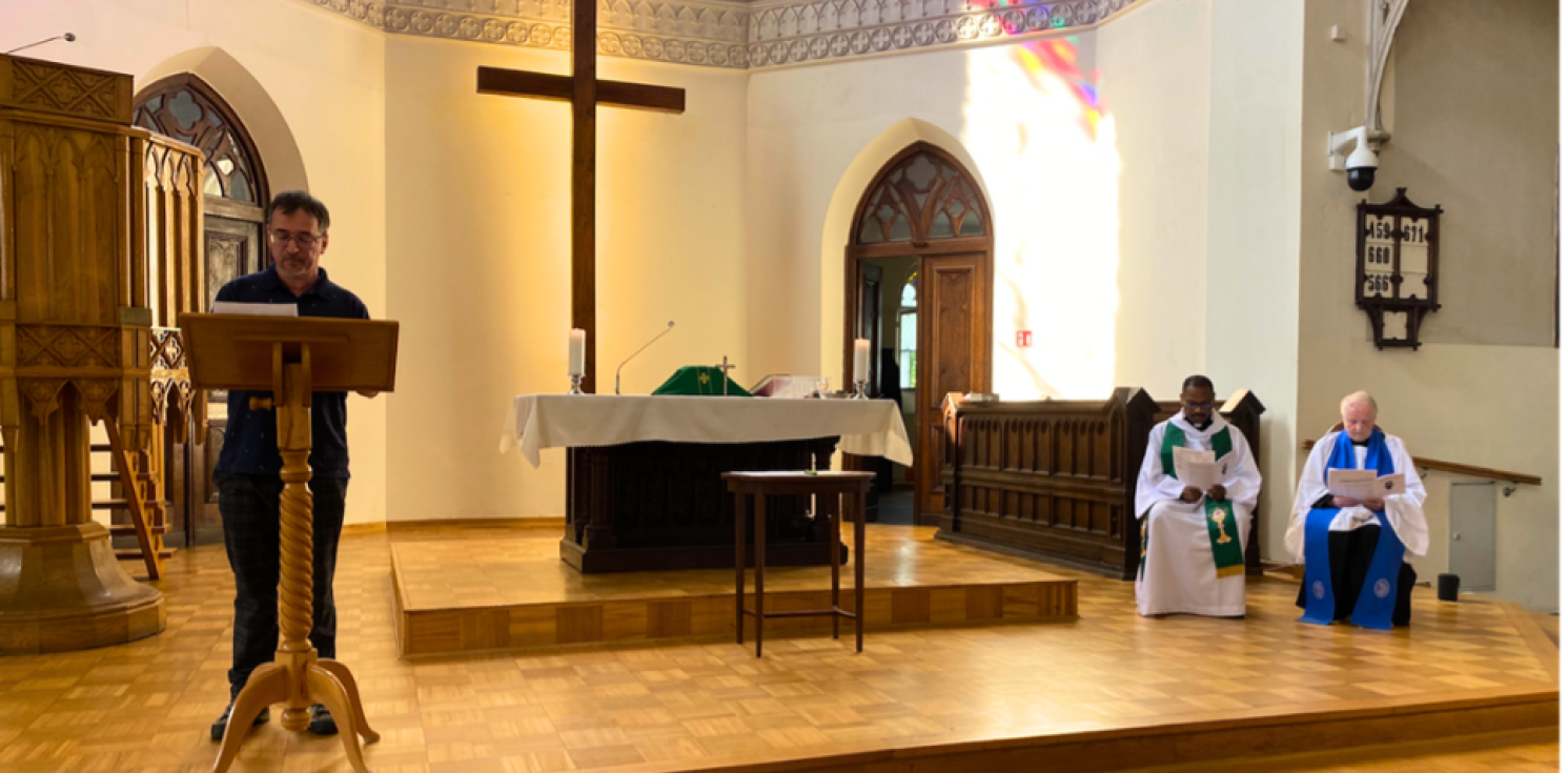 A reader at the front of church and two clergy sit