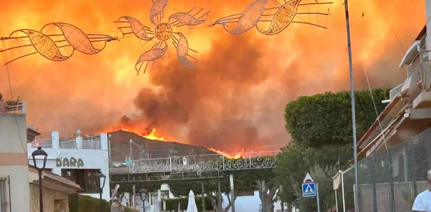 fire fills the sky behind shops