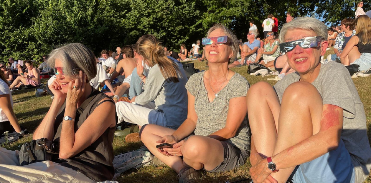 people in a park with eclipse glasses on