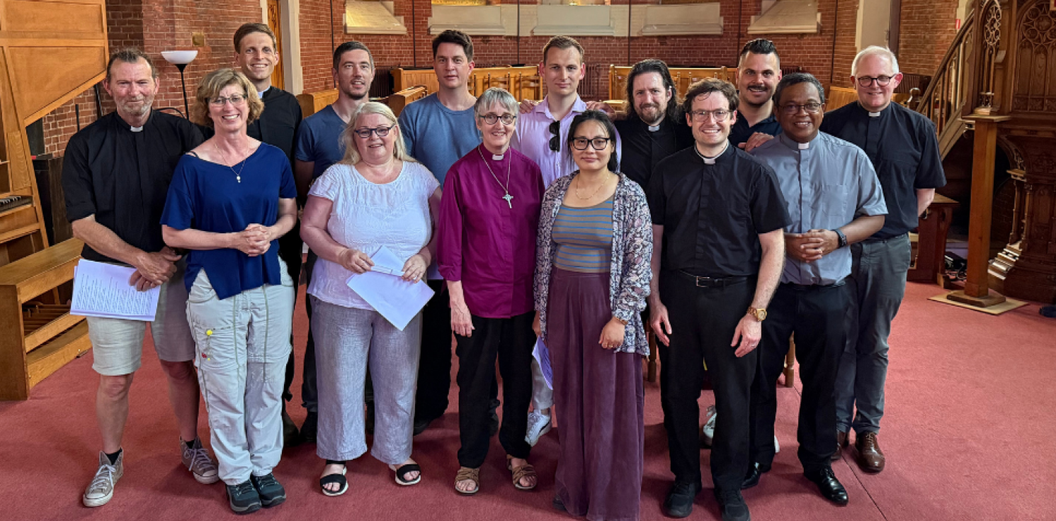 A group of ordinands stand facing camera at the front of the inside of a church