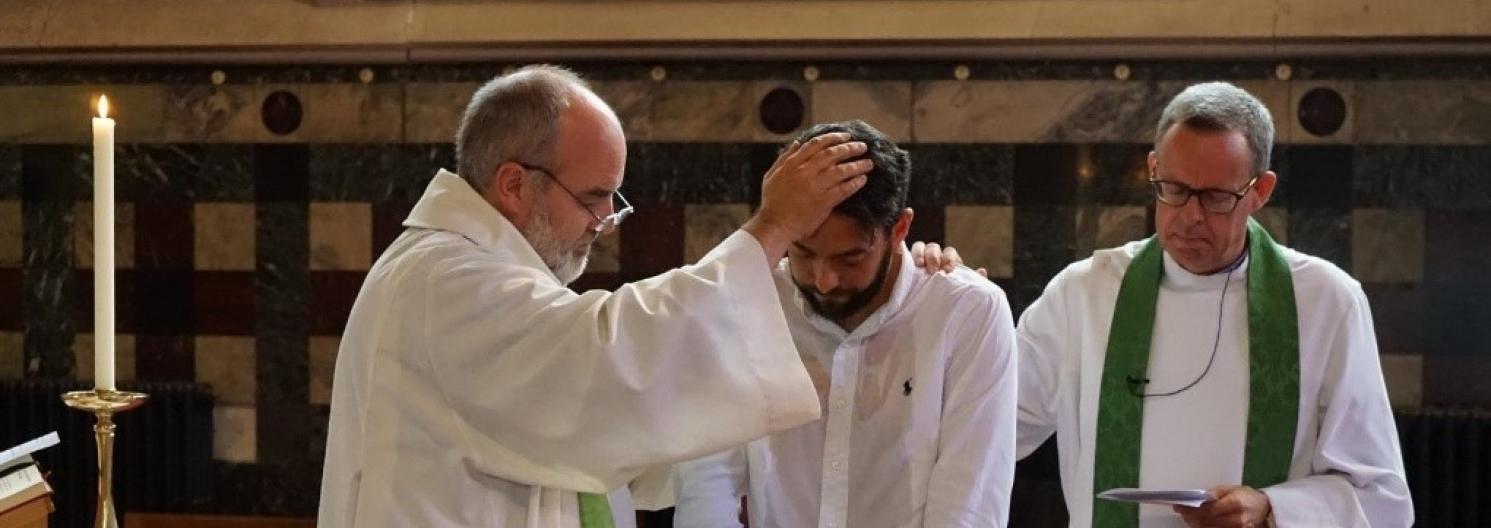 Two clergy performing and adult baptism in church.
