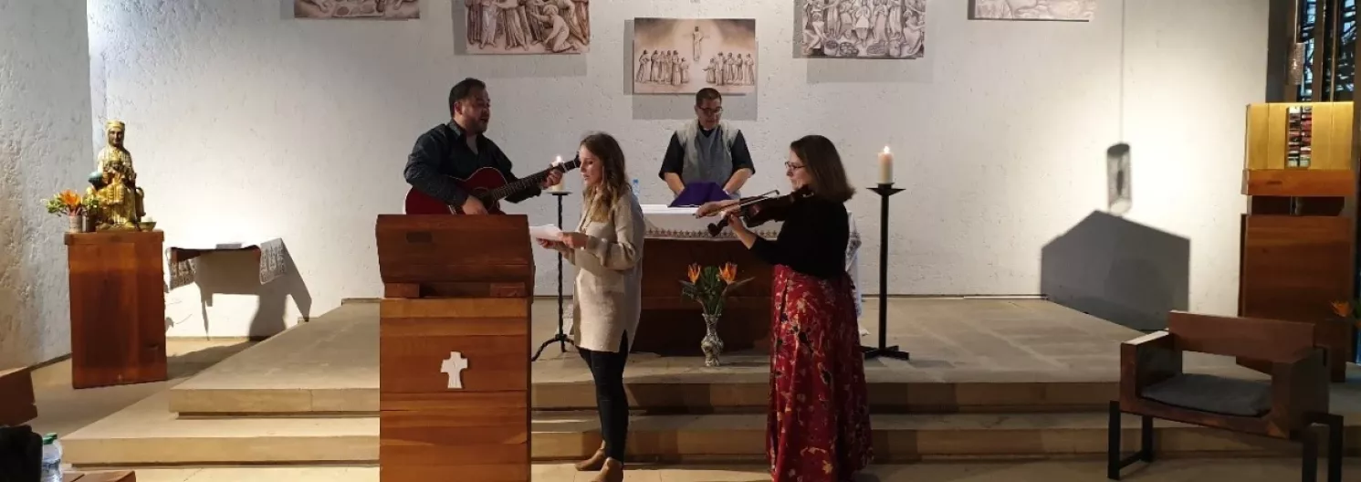 People singing and playing guitar at the front of a church.