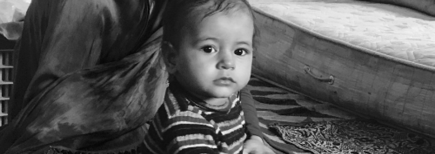 A mono image of an infant held by their mother