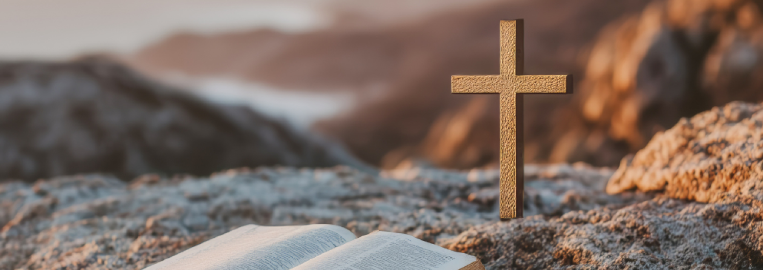 A small cross and an open bible on a hill top