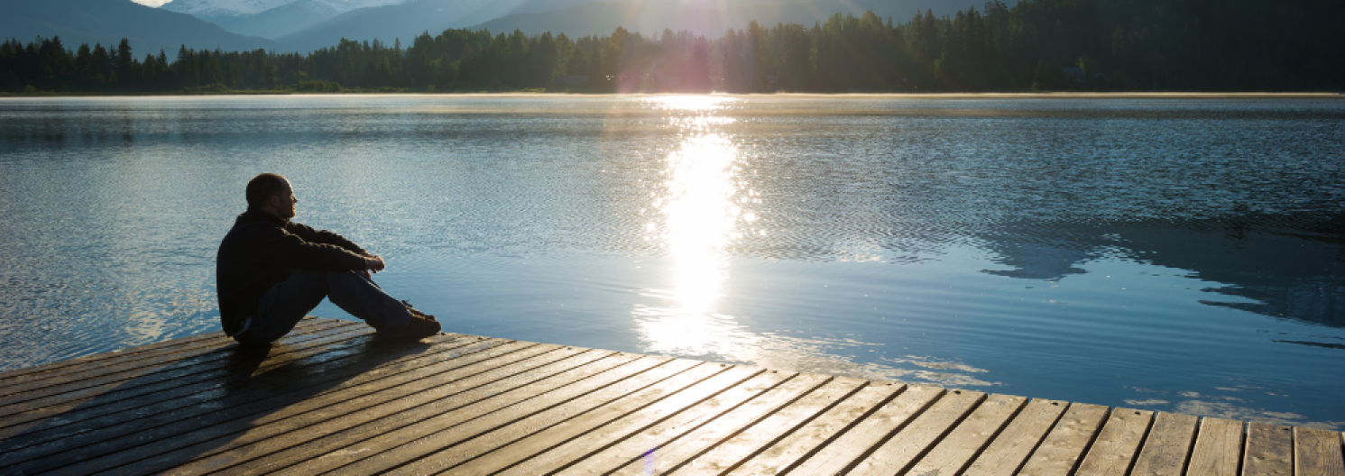 someone sitting on a pier looking at a lake