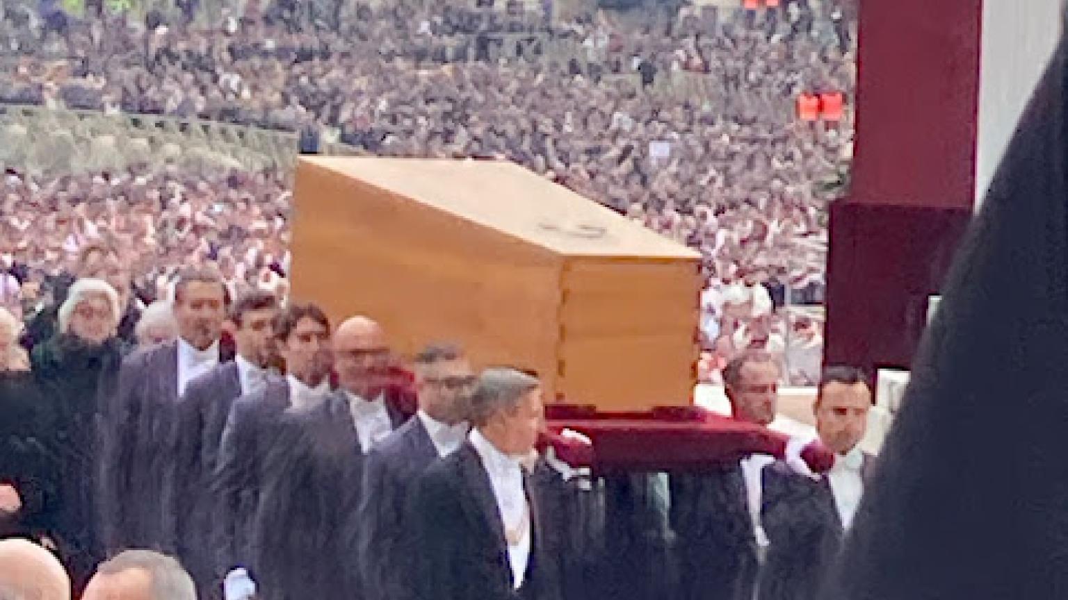 The popes coffin being carried through the crowds.