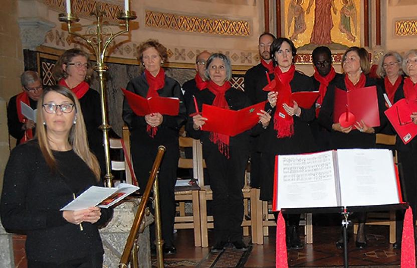 A choir group dressed in red and black stand ready to perform.