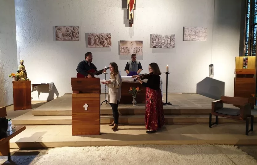 People singing and playing guitar at the front of a church.