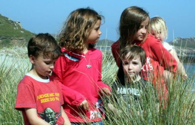 Five children stood on a sunny beach.