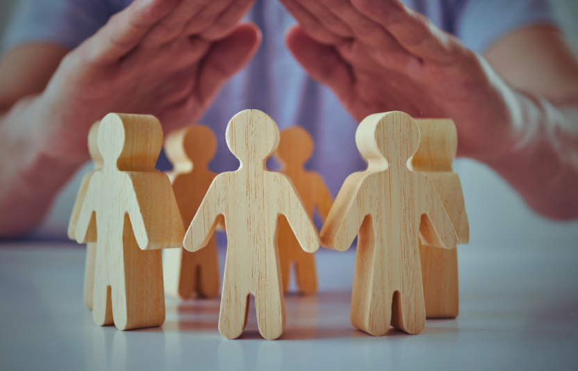 Wooden cut out people protected by hands