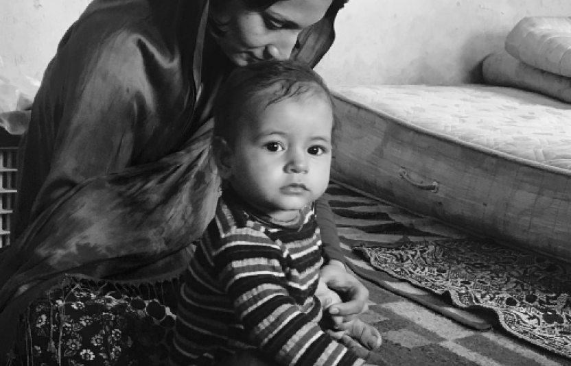 A mono image of an infant held by their mother