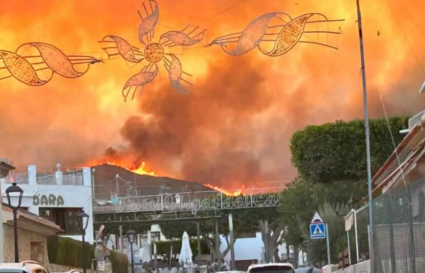 fire fills the sky behind shops
