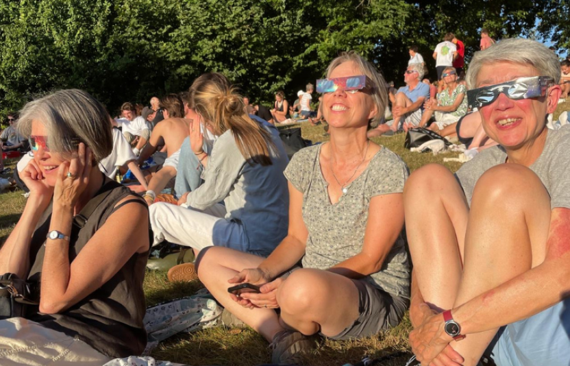 people in a park with eclipse glasses on