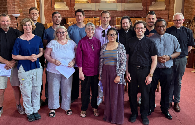 A group of ordinands stand facing camera at the front of the inside of a church
