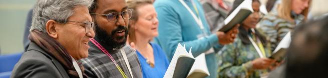 People singing at a conference holding books